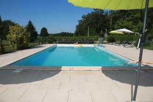 a large swimming pool with an umbrella and chairs at Papillon in Sainte-Mondane