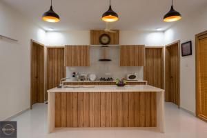 a kitchen with wooden cabinets and a clock on the wall at Reunion Ocean Elite - Beach House in Udupi