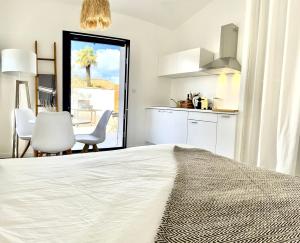 1 dormitorio con 1 cama blanca grande y cocina en Maisonnette à proximité plage et port de St-Martin, en Saint-Martin-de-Ré