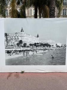 a black and white photo of a beach with people in the water at Cannes, la Croisette, Palais Miramar in Cannes