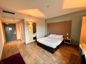 a bedroom with a large bed and wooden floors at Campanile Metz Nord Woippy- Porte du Luxembourg A31- Confort Climatisé- Air Conditionning in Woippy