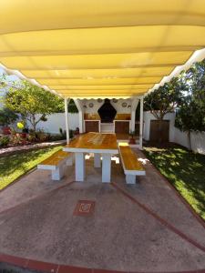 a picnic table with benches under a yellow canopy at Can Che in Cala Galdana