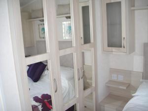 a room with some glass shelves and a bed at Bri-ann's Seaside Holiday Home NO VANS OR LARGE VEHICLES in Selsey