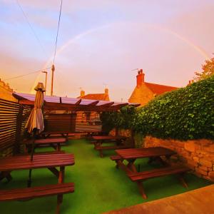 uma fila de mesas de piquenique com um arco-íris ao fundo em T-post guest house em South Milford