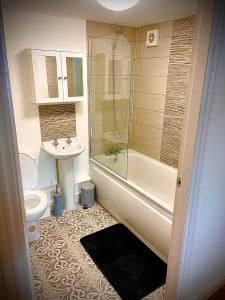 ein Badezimmer mit einer Badewanne, einem Waschbecken und einem WC in der Unterkunft T-post guest house in South Milford