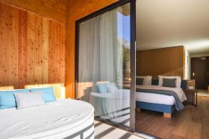 een slaapkamer met 2 bedden en een glazen wand bij Mont Avic Resort & Wellness in Champdepraz