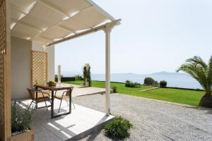 un patio con tavolo, sedie e vista sull'oceano di Villa Itis - Elegant Ground Floor Suite with Terrace & Great View a Neapolis