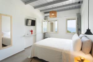 una camera bianca con un letto e due finestre di Villa Itis - Elegant Ground Floor Suite with Terrace & Great View a Neapolis