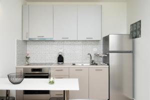 una cucina con armadietti bianchi e frigorifero di Villa Itis - Elegant Ground Floor Suite with Terrace & Great View a Neapolis