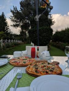 two pizzas on a table with plates and glasses at The Trevene Hotel in Nuwara Eliya