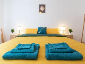 a large yellow bed with blue towels on it at LE STELLA - HYPERCENTRE GARAGE GRATUIT WiFi NETFLIX AMAZON PRIME PROCHE PARC TETE D'OR in Villeurbanne