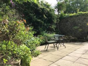 Woodland cottage in Cornwall with walled garden في هيلستون: فناء مع طاولة وكراسي في حديقة