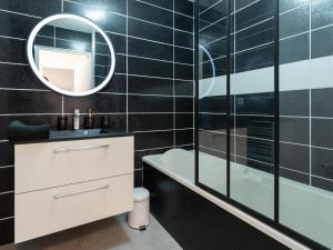 a bathroom with a tub and a sink and a mirror at LE STELLA - HYPERCENTRE GARAGE GRATUIT WiFi NETFLIX AMAZON PRIME PROCHE PARC TETE D'OR in Villeurbanne