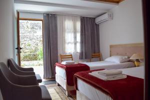 Habitación de hotel con 2 camas y ventana en Sokaku i te Marreve GuestHouse, en Gjirokastra