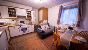 a kitchen and dining room with a table and a couch at Rowrah Hall - The Old Dairy in Rowrah