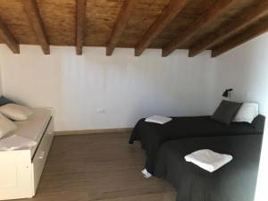a bedroom with two beds and a couch and wooden ceilings at El Rincon de Cabello in Sierra