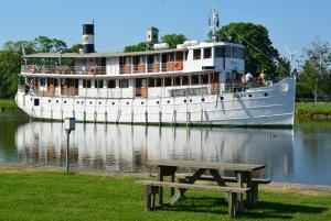 ein großes Boot im Wasser mit einem Picknicktisch in der Unterkunft Pensionat Åsgården in Lyrestad