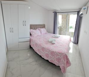 a bedroom with a bed with a pink bedspread at PORTO DE GALINHAS MAKAMBIRA RESIDENCE in Porto De Galinhas