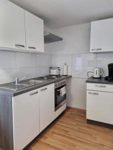 - une cuisine avec des placards blancs et un évier dans l'établissement KM3 Apartment, à Triberg
