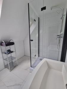 La salle de bains blanche est pourvue d'une douche et d'une baignoire. dans l'établissement KM3 Apartment, à Triberg