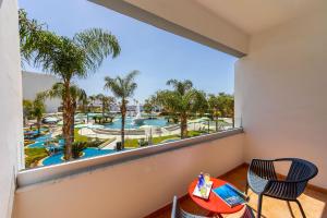 a balcony with a view of the pool and palm trees at Faros Hotel Ayia Napa in Ayia Napa