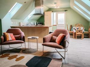 a living room with two chairs and a kitchen at Aite-Sithiel in Kingsburgh