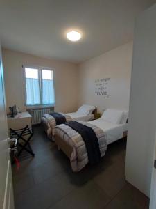 a room with two beds and a table and windows at Braschi 8 B&B in Zola Predosa