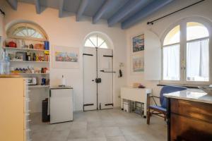 アルゲーロにあるAlghero Fish Houseの白い壁のキッチン、アーチ型の窓2つ