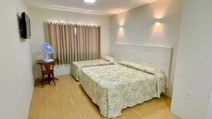 a bedroom with two beds and a table with a fan at Hotel Nascentes da Serra in Poços de Caldas +28 photos