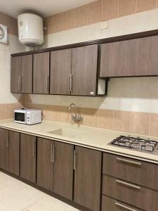 a kitchen with wooden cabinets and a microwave at أركانا للشقق المخدومة in Tabuk