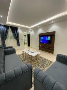 a living room with a couch and a flat screen tv at أركانا للشقق المخدومة in Tabuk