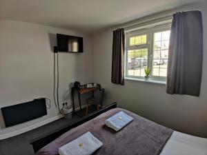 a bedroom with a bed and a tv and a window at Woolpack Inn in Chichester