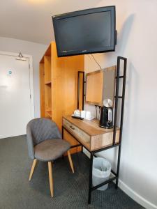 a desk with a chair and a television on a wall at Woolpack Inn in Chichester