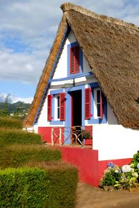 a red white and blue house with a thatched roof at Hotel Quinta Do Furao in Santana