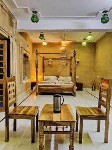 Zimmer mit 2 Stühlen, 1 Bett und 2 Tischen in der Unterkunft Golden Marigold Hotel in Jaisalmer
