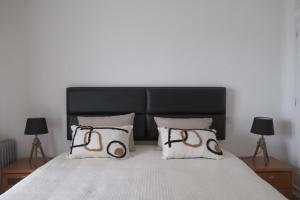 a bed with a black headboard and two pillows at ML Carvoeiro Mar Apartment in Carvoeiro