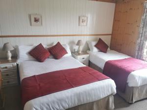 una camera con due letti con lenzuola rosse e bianche di The Olde Castle B&B a Renvyle