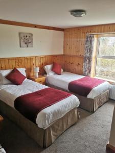 2 camas en una habitación de hotel con ventana en The Olde Castle B&B, en Renvyle
