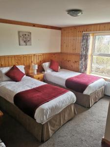 due letti in una camera d'albergo con finestra di The Olde Castle B&B a Renvyle