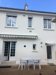 una casa bianca con un tavolo e sedie di fronte di « Chez Annie » a Doué-la-Fontaine