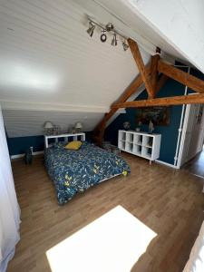 een slaapkamer met een bed, blauwe muren en houten vloeren bij A la bon'Eure in Nassandres