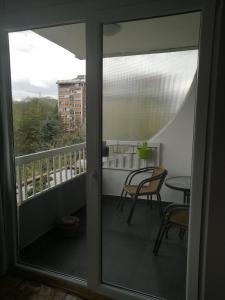 a balcony with a glass door with a table and chairs at Green in Belgrade