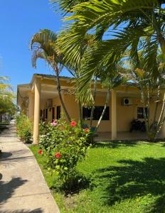 una casa amarilla con palmeras y una acera en Hotel Viña del Mar Omoa, en Omoa