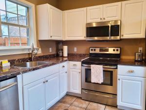 a kitchen with white cabinets and a stove and a sink at Cozy House near Ole Miss & M-Trade! in Oxford +11 photos