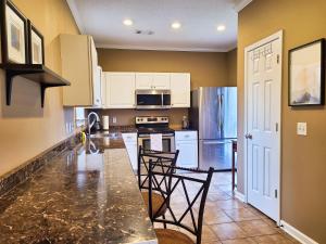 cocina con encimera con sillas y nevera en Cozy House near Ole Miss & M-Trade! en Oxford