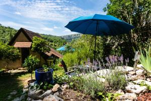 un parasol bleu dans un jardin fleuri dans l'établissement Gîtes Un Jardin dans la Falaise, à Cabrerets