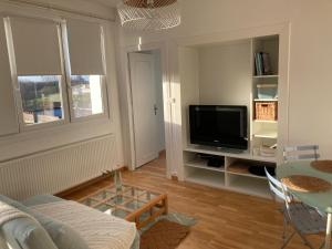 a living room with a couch and a tv at Très bel appartement vue Mer - Les Ilots bleus - Dunkerque Malo les Bains in Dunkerque