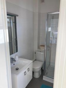 La salle de bains blanche est pourvue d'une douche et de toilettes. dans l'établissement Très bel appartement vue Mer - Les Ilots bleus - Dunkerque Malo les Bains, à Dunkerque