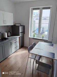 a kitchen with a table and chairs and two windows at Apartament Anastazja in Koszalin
