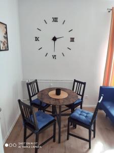 a table and chairs with a clock on a wall at Apartament Anastazja in Koszalin